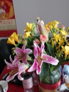 出一束美丽的鲜花，包括粉色和黄色的百合花和橙色的康乃馨。花瓶