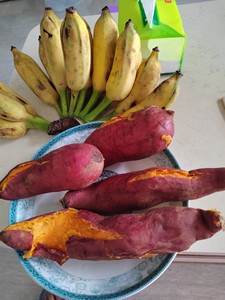 出一堆新鲜的水果，其中包括了一些黄色的香蕉和紫色的山地瓜。这