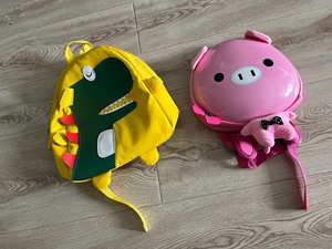 出粉色小猪的儿童背包，品牌是Trunki。还有黄色书包，这款