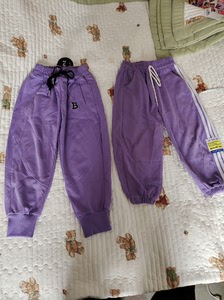 两条紫色运动裤。棉的料子，左边全新的束脚款裤长60。背后裤脚